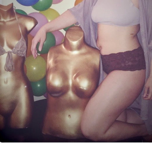 Person wearing Birthday Suit Shop lingerie next to a mannequin with balloons in the background