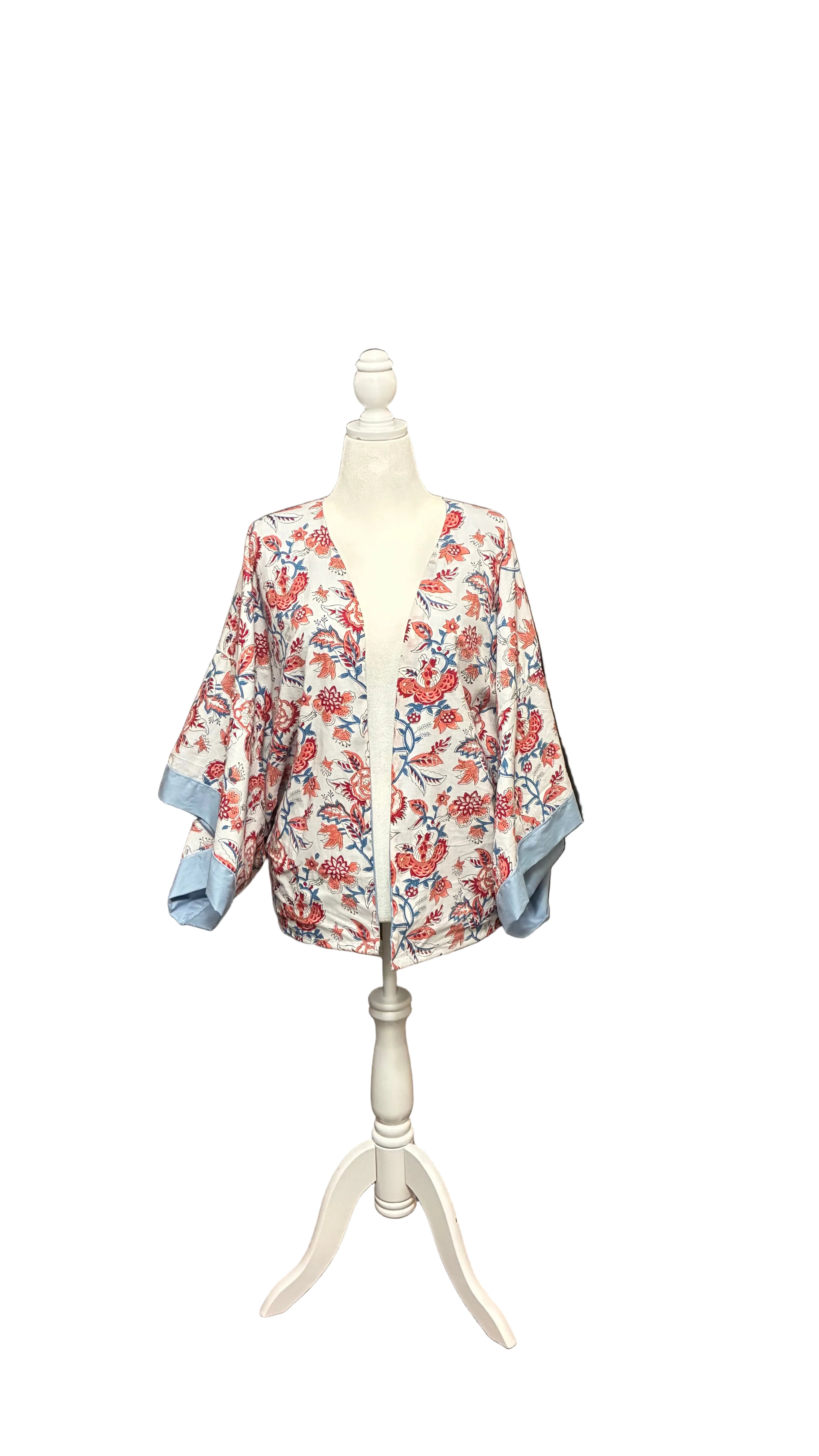 Floral kimono on a mannequin stand in a room with orange curtains and clothing racks.