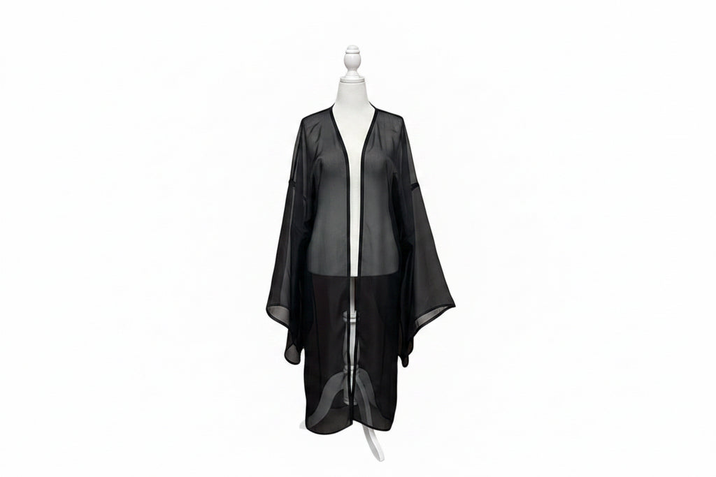 A black sheer mesh robe or kimono-style cover-up displayed on a white dress form mannequin, set against a red-orange curtain backdrop.