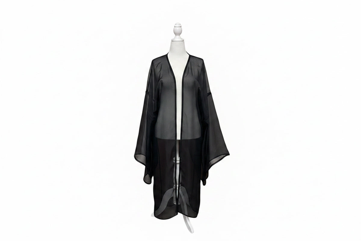 A black sheer mesh robe or kimono-style cover-up displayed on a white dress form mannequin, set against a red-orange curtain backdrop.