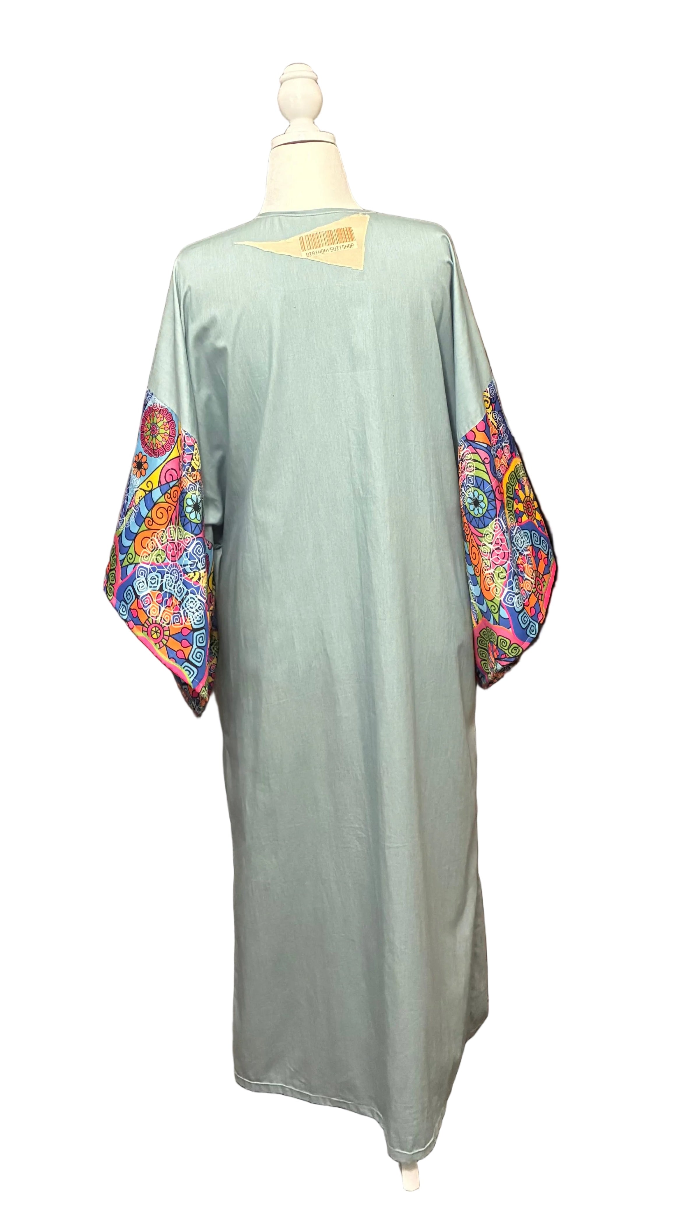 Light green kaftan with colorful floral sleeves on a mannequin against a white background