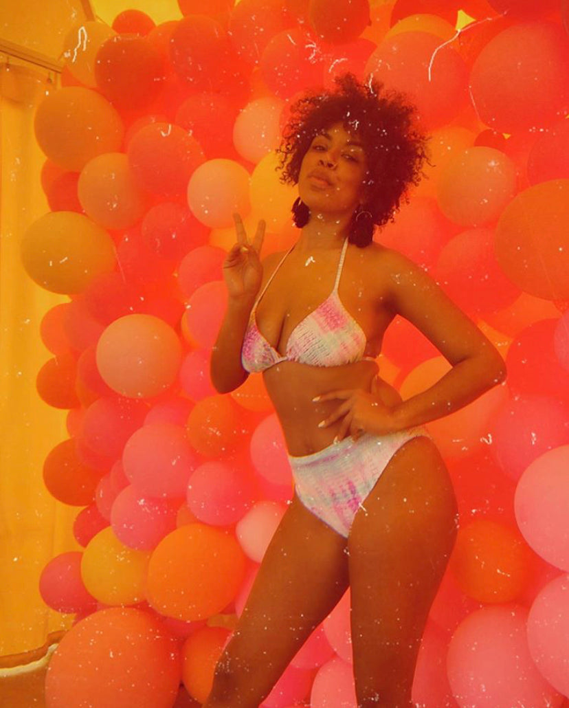 Woman in a bikini standing among colorful balloons